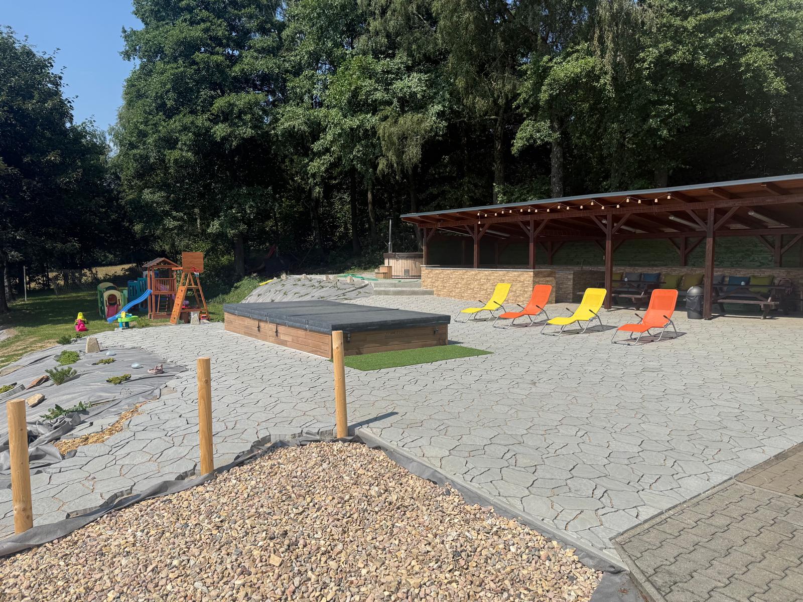 Sluneční terasa s lehátky před krytou pergolou